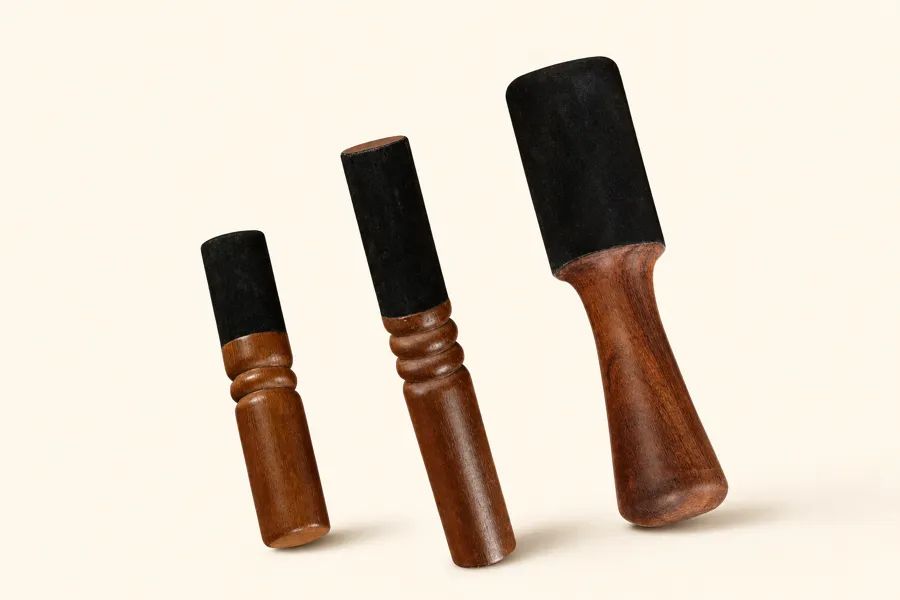 Three leather-headed singing bowl mallets lined up from small to large head