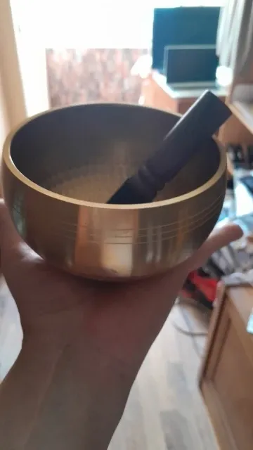 Verified buyer photo: 8 cm brass singing bowl held in one hand at home, striker resting inside